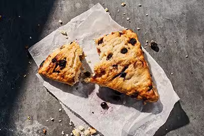 Picture of a blueberry scone on a napkin. part of it is torn off.